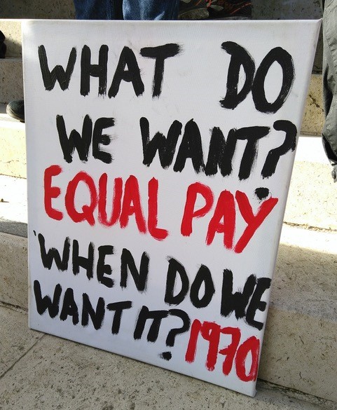 A sign reads: What do we want? Equal pay, When do we want it? 1970