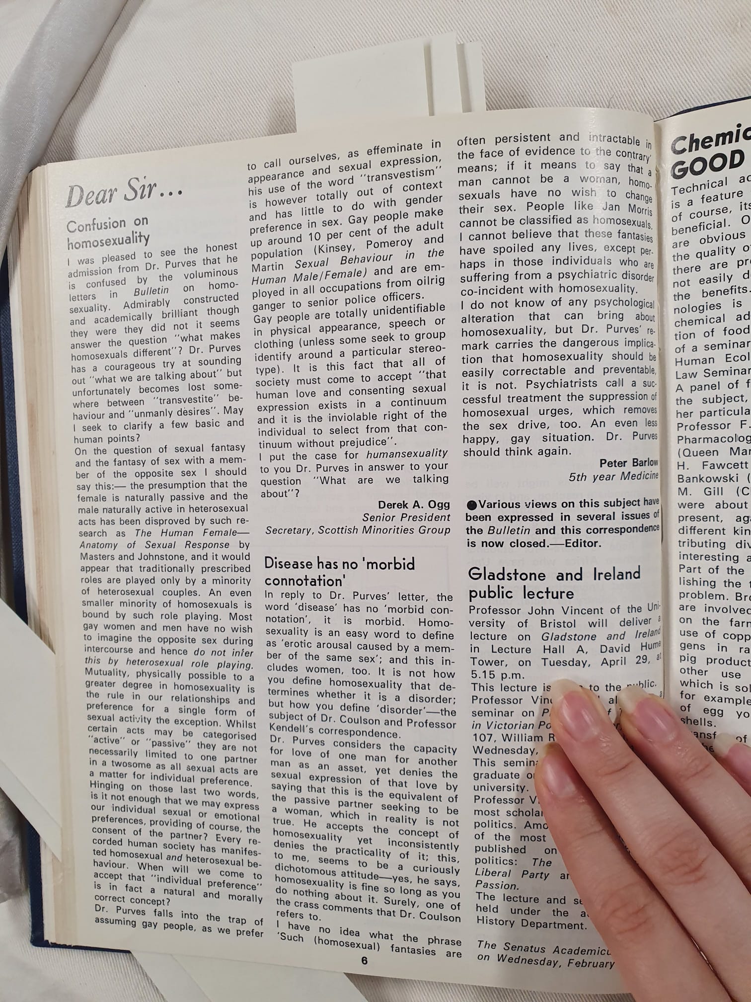 Hand holding down an archival newspaper