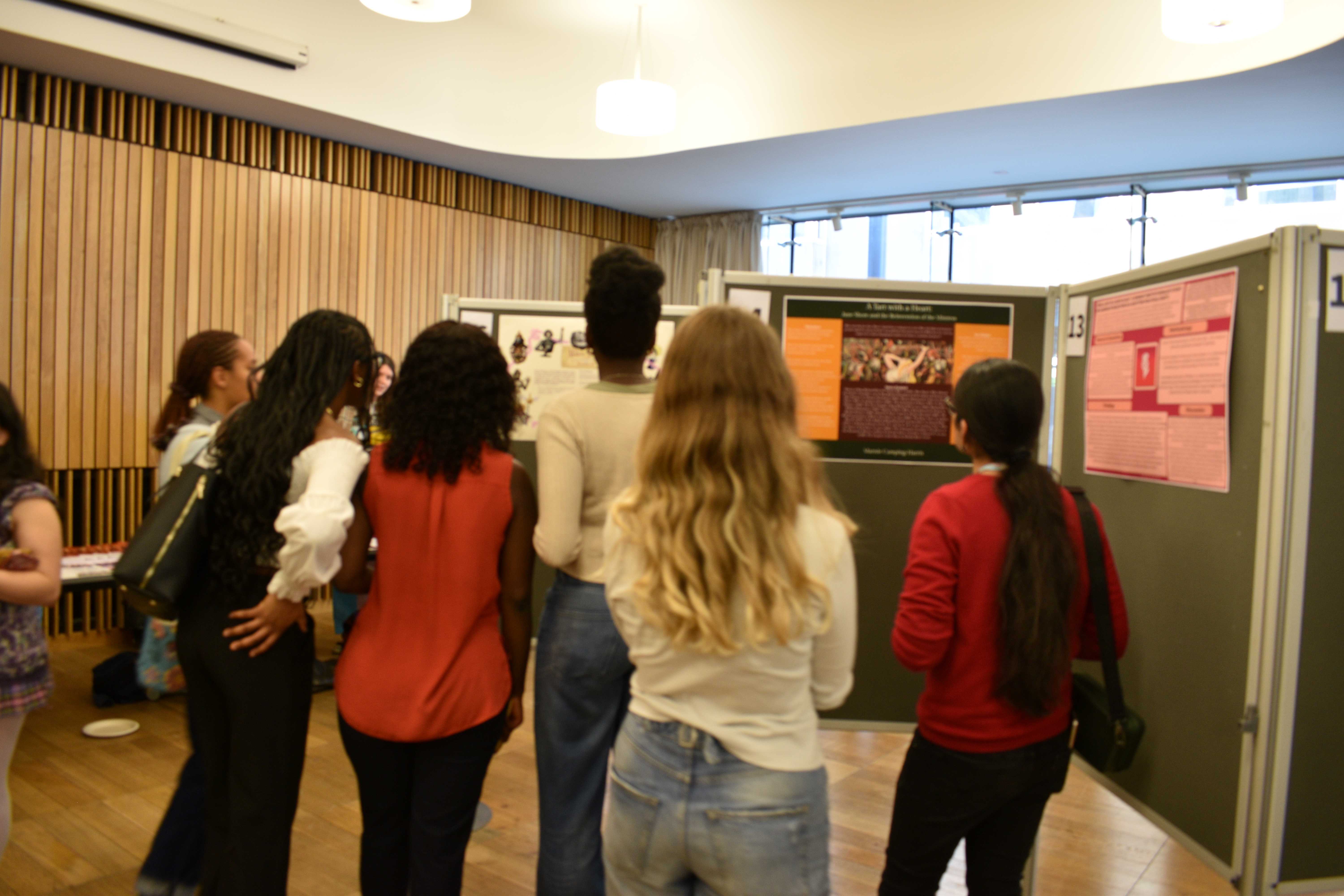 Photo of six undergraduate students looking at a poster by another undergraduate student at the Mini Undergraduate Dissertation Showcase.