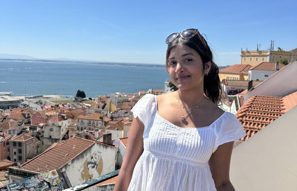 Tulsa smiling into the camera, against a sea on a sunny day